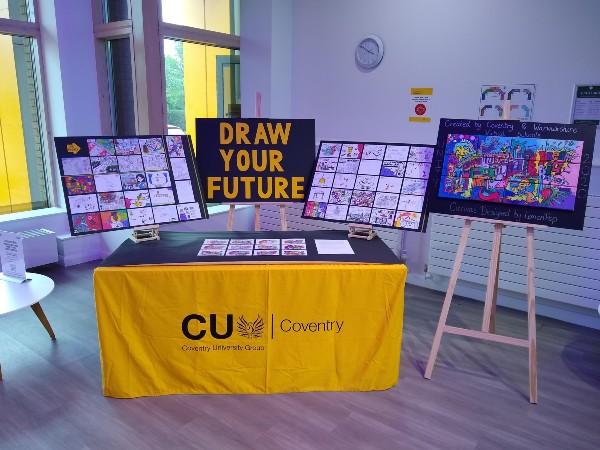 Table top display with Coventry University banner and art work behind on display.