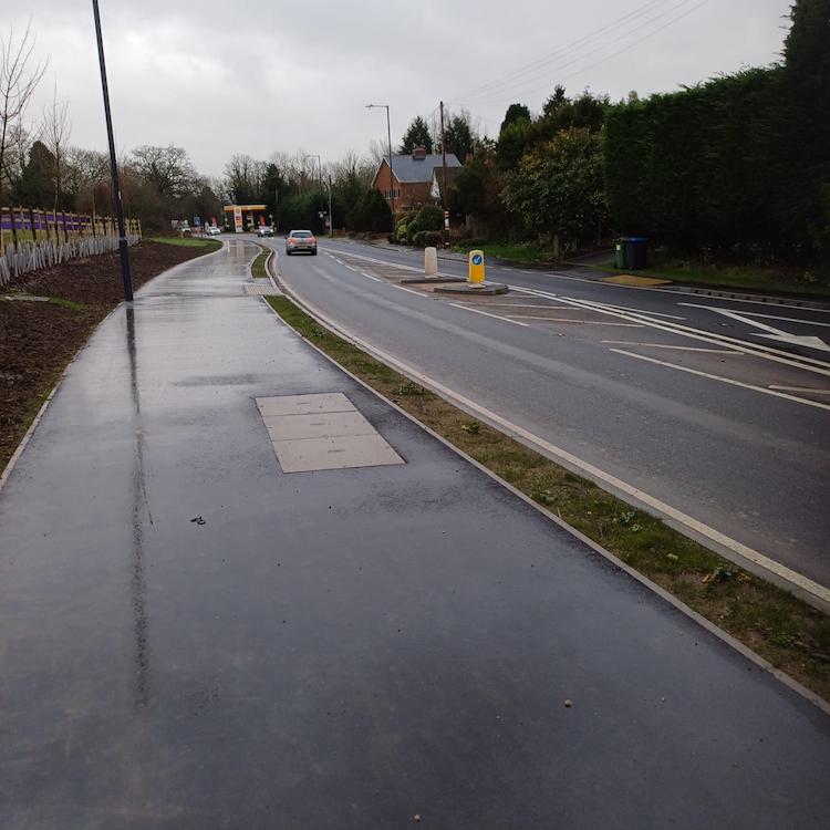 Image of the completed road and pavement improvements showing a car and a crossing point