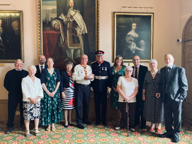 Douglas Shorter (centre) being presented with his British Empire Medal by Lord Lieutenant Tim Cox, alongside family and friends.  