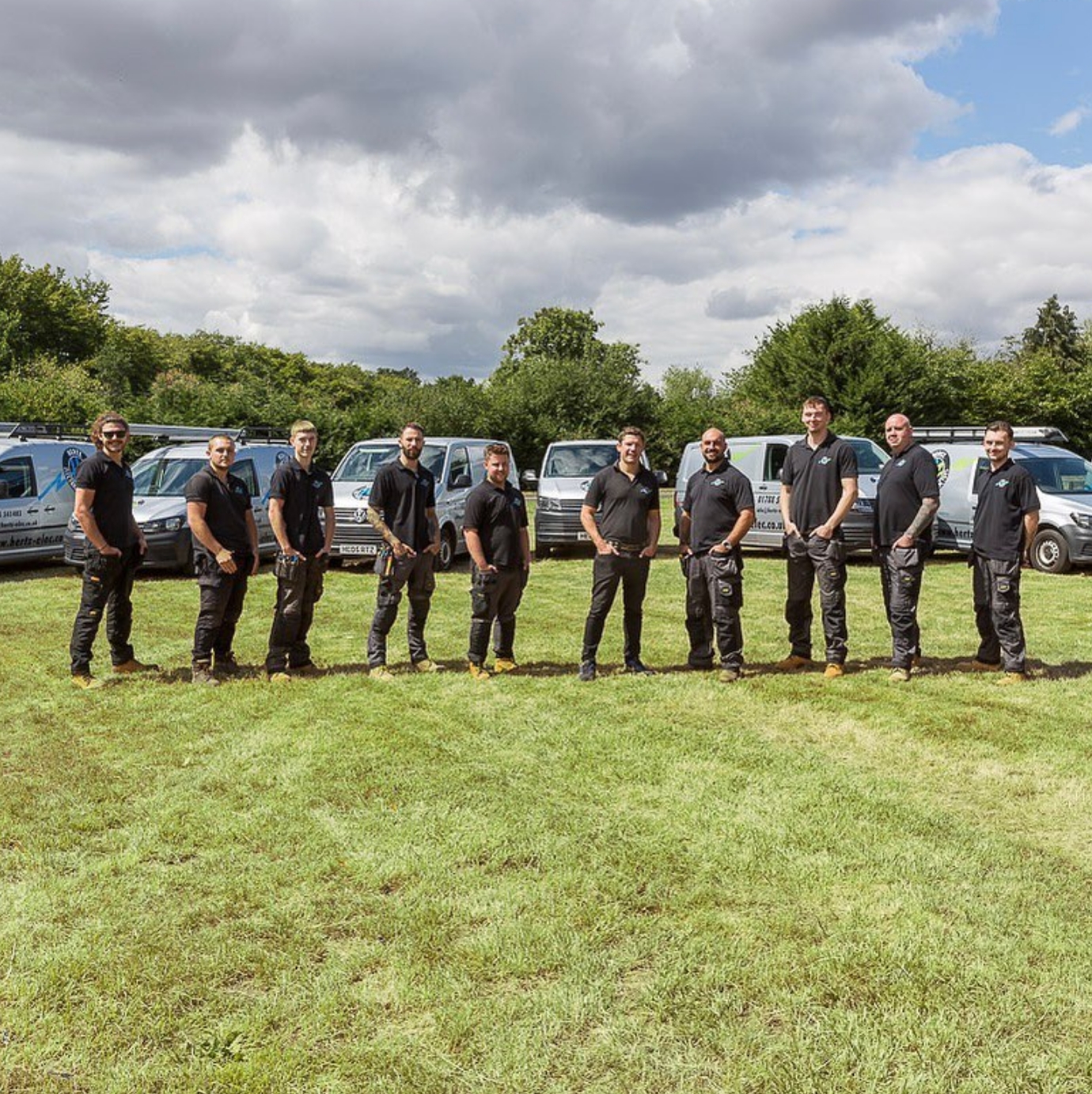 Staff of Hertz Electrical Contractors Ltd standing in a row in front of company vehicles