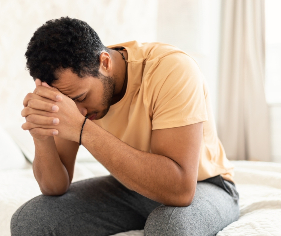 A distressed man is sat with his head in his hands due to sexual abuse.