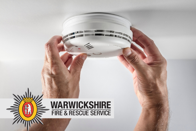 Image of someones hand fitting a smoke alarm on a ceiling