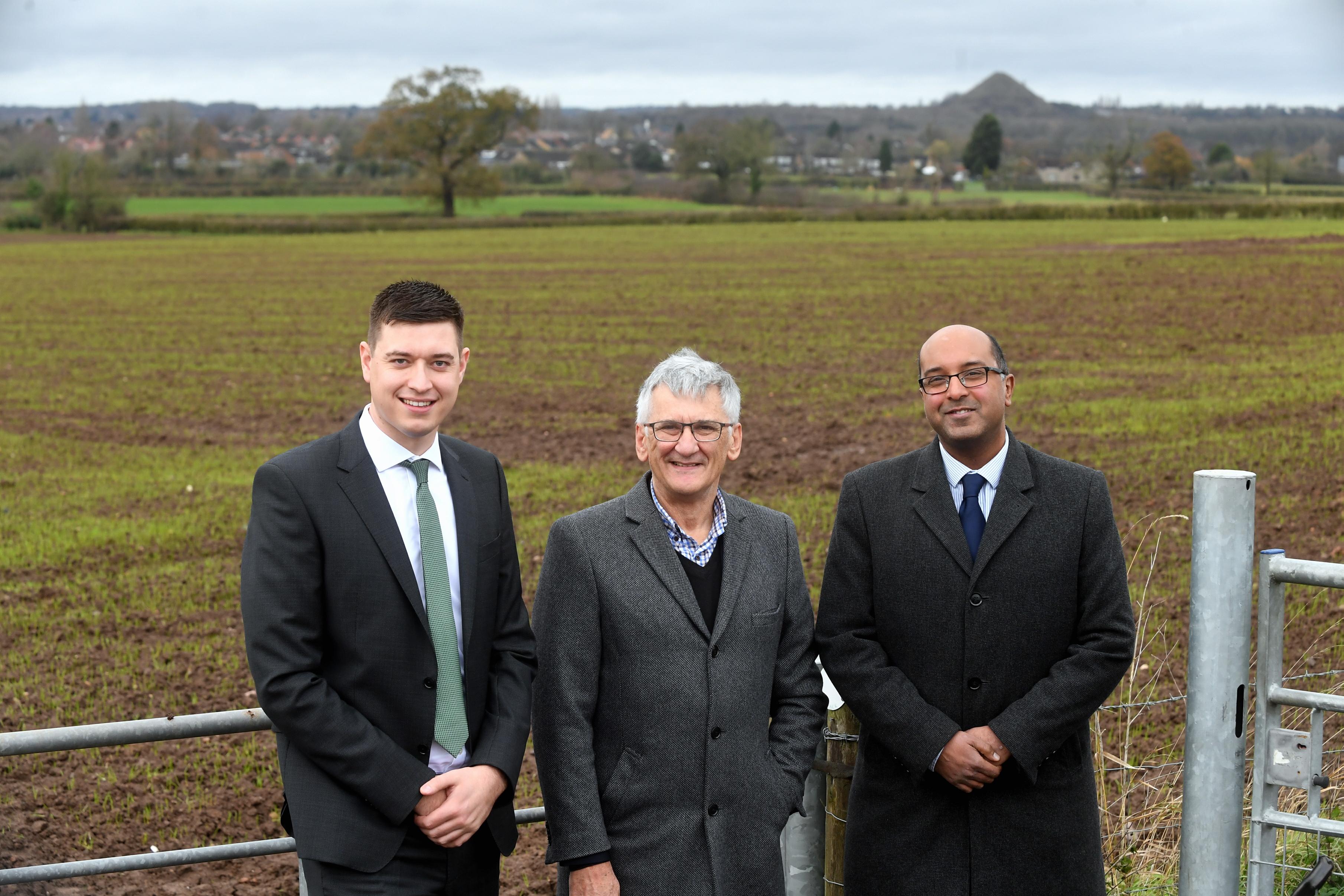 A photograph of three men in front of a field. From left to right: Adam Daniels, Peter Butlin and Stuart Buckley
