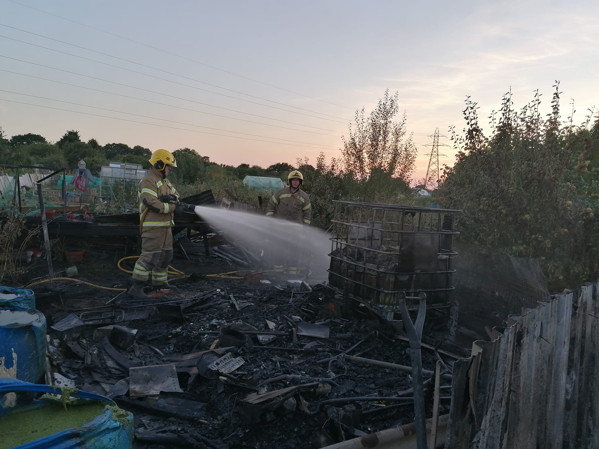 Firefighters work on a fire as the sunsets in the background