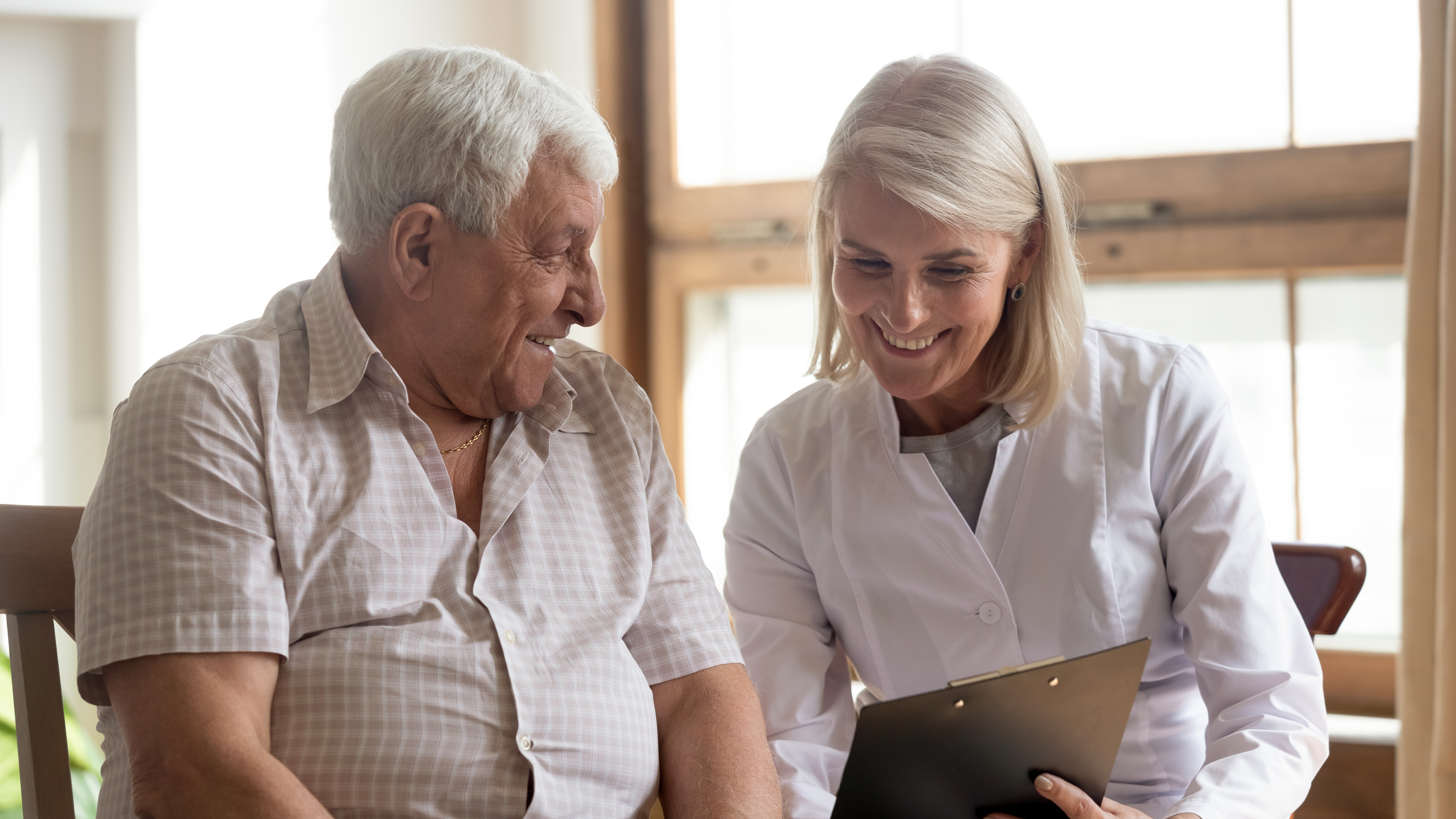 A man and woman chatting and smiling whilst looking at a clipboard