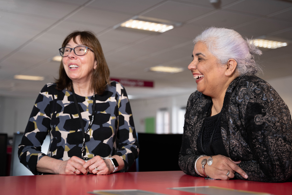 two women sat at a communal desk in offices.